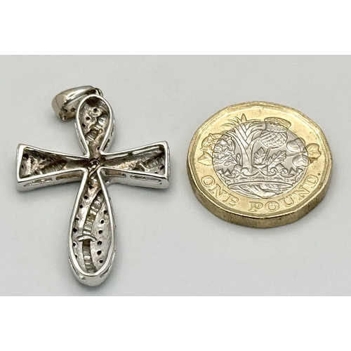 61 - An 18K White Gold Diamond Set Cross Pendant. A combination of tapered baguette, round and princess c... 