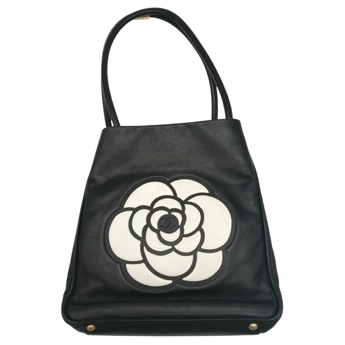 241 - A Chanel Black Leather Tote Bag. Black leather exterior with white leather Camellia flower and CHANE... 