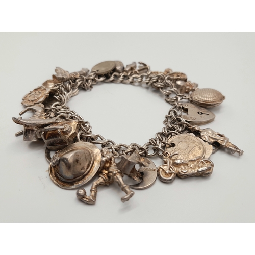 140 - Vintage SILVER CHARM BRACELET complete with Silver safety chain. Having 31 charms to include  Man in... 