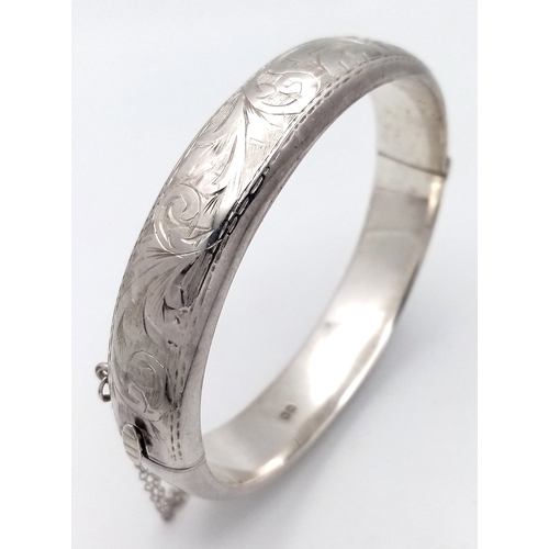 1310 - A vintage sterling silver click-on bangle (include safety chain) with floral motif engravings. Full ... 