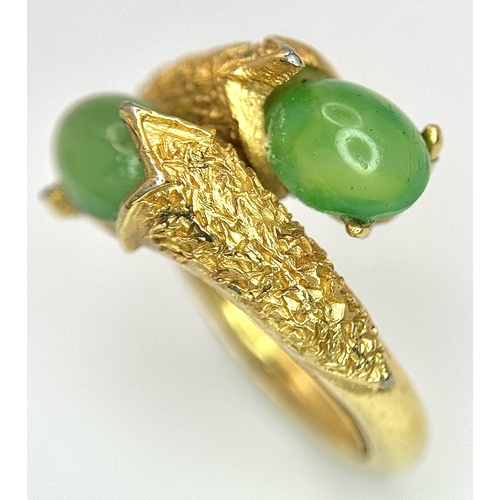 411 - An 18K Gold (tested) Jade Twist Ring. Serpentine in nature with twin jade cabochons. Size O 1/2. 5.3... 