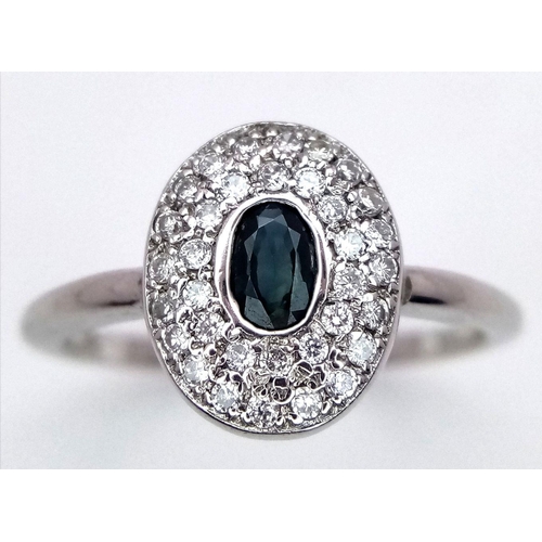 364 - An 18K White Gold Emerald and Diamond Ring. Central oval cut emerald with a diamond cluster surround... 