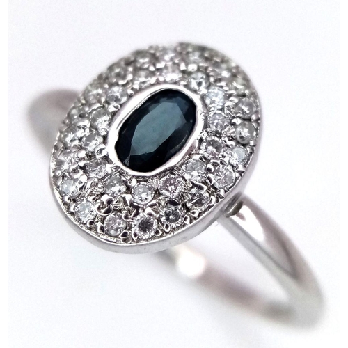 364 - An 18K White Gold Emerald and Diamond Ring. Central oval cut emerald with a diamond cluster surround... 