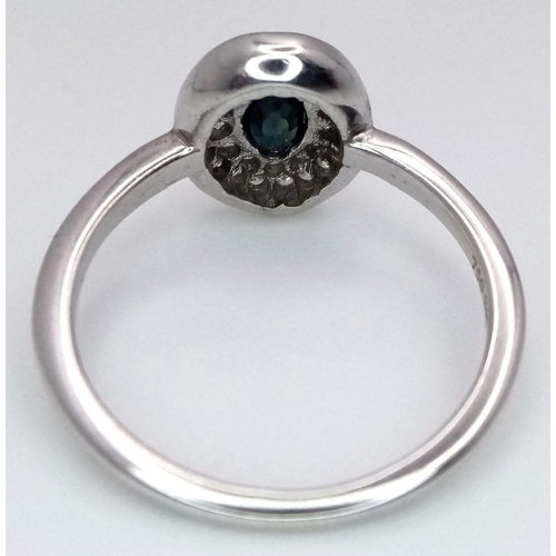364 - An 18K White Gold Emerald and Diamond Ring. Central oval cut emerald with a diamond cluster surround... 