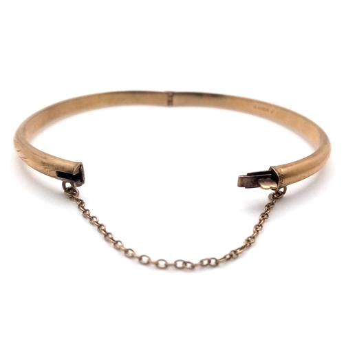 244 - A Vintage 9K Yellow Gold Bangle. Clip design and safety chain. 6.7g.