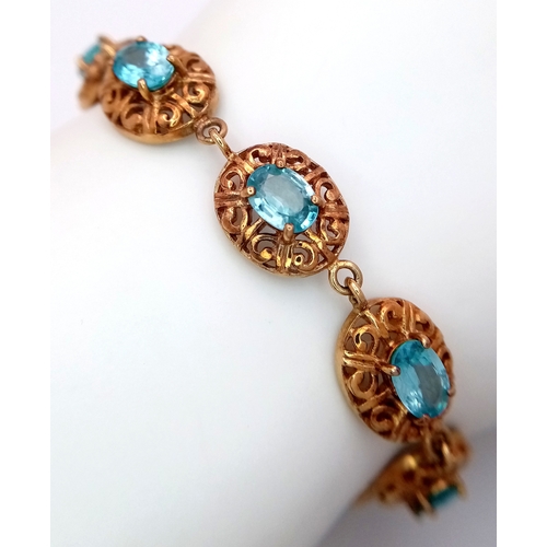 16 - A 9k Gold Aquamarine Fancy Link Bracelet. Ten ice blue oval cut gemstones. 18cm. 15.7g