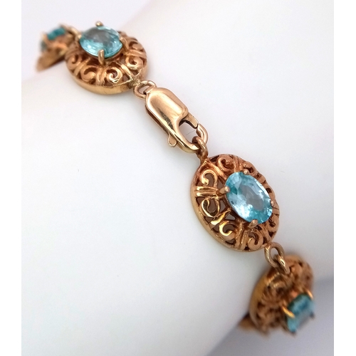 16 - A 9k Gold Aquamarine Fancy Link Bracelet. Ten ice blue oval cut gemstones. 18cm. 15.7g