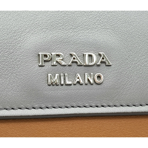 229 - A Prada Milano Two-Tone Leather Tote Bag. Grey and tan smooth leather exterior with silver-toned har... 