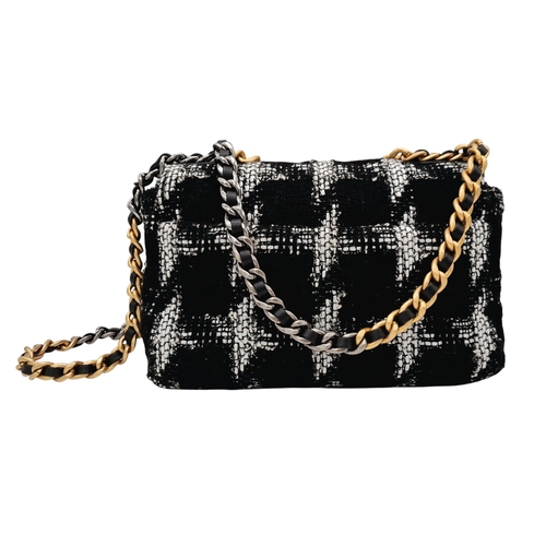 34 - A Chanel Black and White Tweed Flap Bag. Quilted tweed exterior with gold toned hardware, leather-in... 