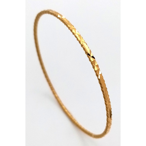 52 - An 18K Yellow Gold (test as) Bangle with Geometric Pattern. 3mm width. 65mm inner diameter. 10.1g.
