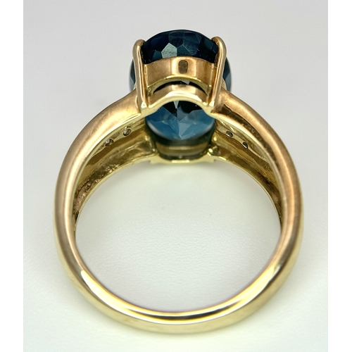 262 - A 9K Yellow Gold, London Blue Topaz and Diamond Ring. A 5.979ct, oval cut topaz with 0.056ct of Diam... 