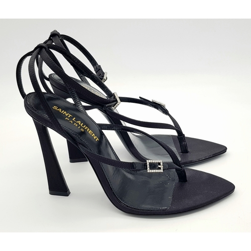 219 - A pair of Saint Laurent strappy heeled sandals. Black satin exterior with leather insoles, featuring... 