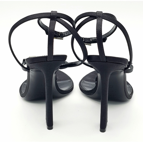 219 - A pair of Saint Laurent strappy heeled sandals. Black satin exterior with leather insoles, featuring... 