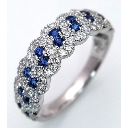 129 - An 18K White Gold, Sapphire and Diamond Cluster Ring. 18 round cut sapphires in diagonal pair form -... 