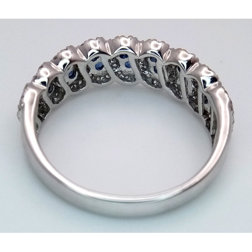 129 - An 18K White Gold, Sapphire and Diamond Cluster Ring. 18 round cut sapphires in diagonal pair form -... 