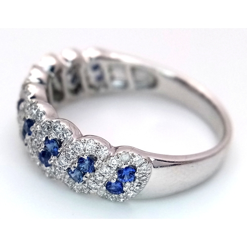 129 - An 18K White Gold, Sapphire and Diamond Cluster Ring. 18 round cut sapphires in diagonal pair form -... 