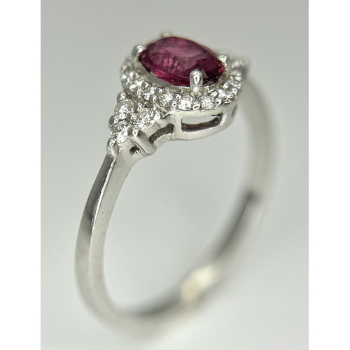 177 - An 18K White Gold, Ruby and Diamond Ring. 0.25ct oval cut high grade central ruby with a diamond clu... 