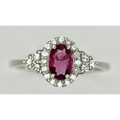 177 - An 18K White Gold, Ruby and Diamond Ring. 0.25ct oval cut high grade central ruby with a diamond clu... 
