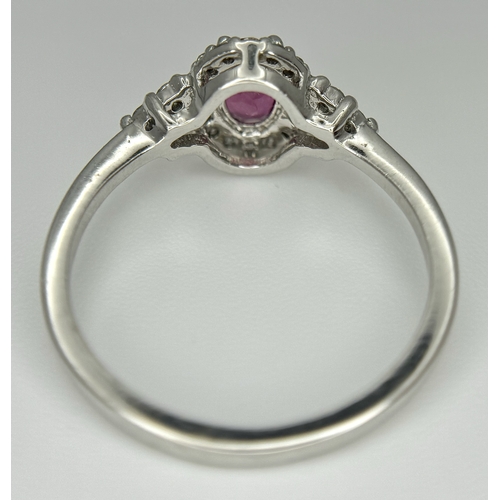 177 - An 18K White Gold, Ruby and Diamond Ring. 0.25ct oval cut high grade central ruby with a diamond clu... 