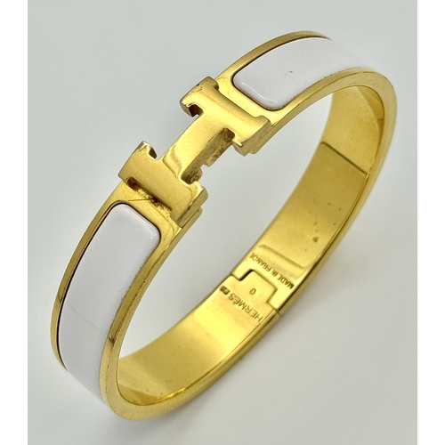 118 - An Hermes Gilded and White Enamel Bangle. 12mm width. Ref: STK024264