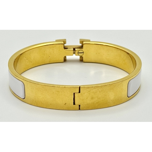 118 - An Hermes Gilded and White Enamel Bangle. 12mm width. Ref: STK024264