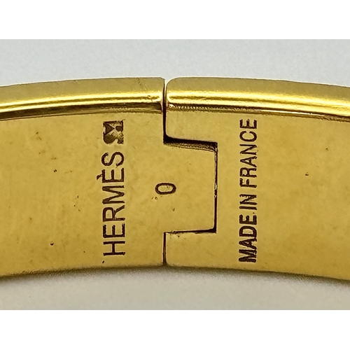118 - An Hermes Gilded and White Enamel Bangle. 12mm width. Ref: STK024264