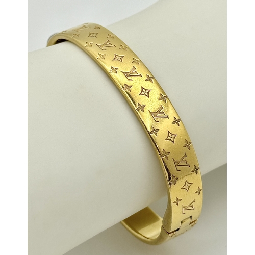 139 - A Louis Vuitton Gilded Bangle. Monogram decoration. 10mm width. Ref: STK024155