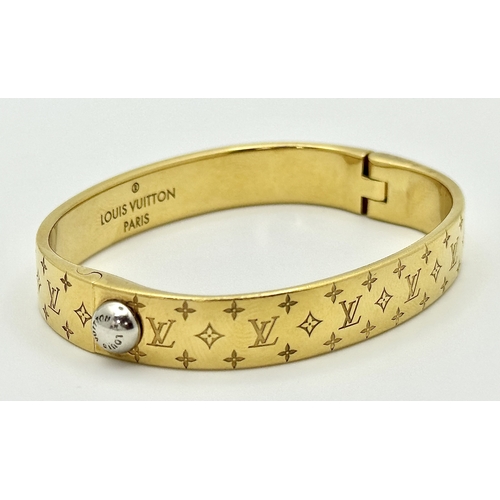 139 - A Louis Vuitton Gilded Bangle. Monogram decoration. 10mm width. Ref: STK024155