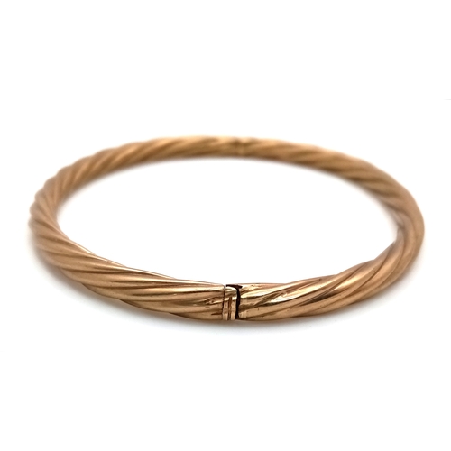 162 - A 9K Yellow Gold Clip Open Bangle. Twist form. 6mm width. 58mm inner diameter. 8.6g.