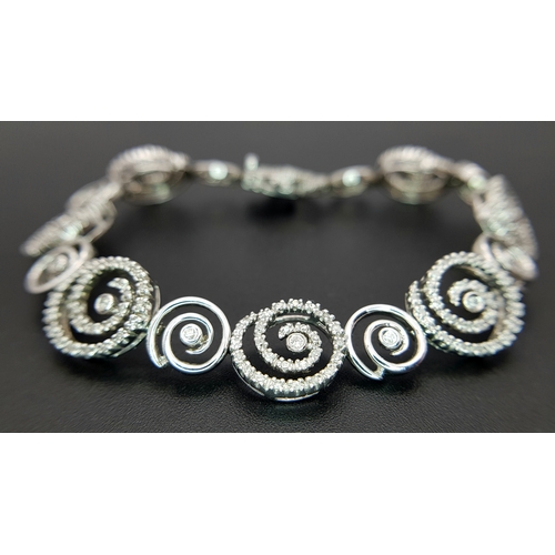 128 - A 14K White Gold Diamond Swirl Tennis Bracelet. c 1.5ctw of round brilliant cut diamonds in a swirl ... 