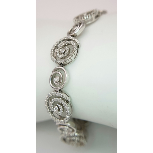 128 - A 14K White Gold Diamond Swirl Tennis Bracelet. c 1.5ctw of round brilliant cut diamonds in a swirl ... 