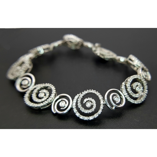 128 - A 14K White Gold Diamond Swirl Tennis Bracelet. c 1.5ctw of round brilliant cut diamonds in a swirl ... 