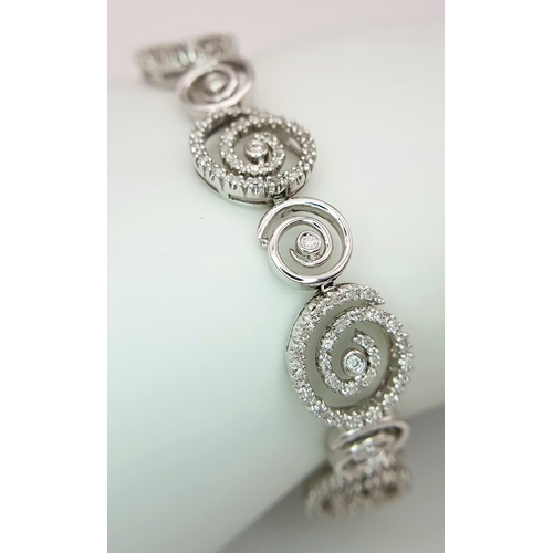 128 - A 14K White Gold Diamond Swirl Tennis Bracelet. c 1.5ctw of round brilliant cut diamonds in a swirl ... 