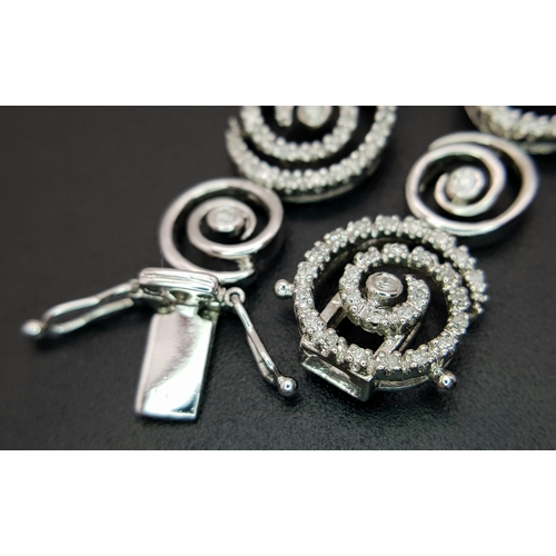 128 - A 14K White Gold Diamond Swirl Tennis Bracelet. c 1.5ctw of round brilliant cut diamonds in a swirl ... 