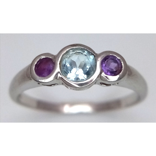 648 - A Stylish Blue Topaz and Amethyst Trilogy Ring, Size S. The Ring is set with a 5mm Round Cut Blue To... 