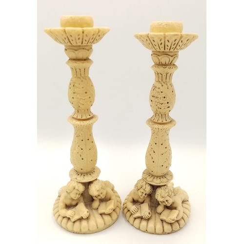 779 - A Pair of Antique Ivorine Candlesticks with Ornate Cherub Decoration. 22cm tall.