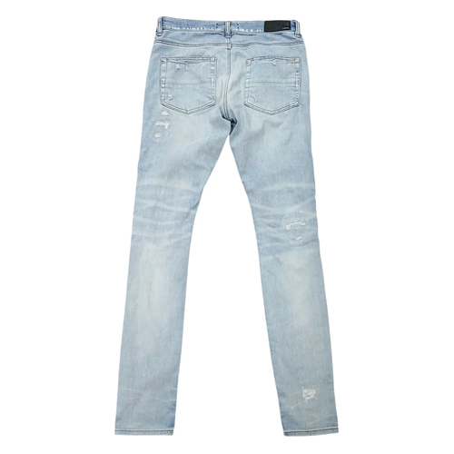 959 - A pair of Amiri light wash distressed skinny jeans featuring heavy ripped details throughout the leg... 