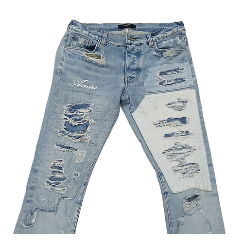 959 - A pair of Amiri light wash distressed skinny jeans featuring heavy ripped details throughout the leg... 