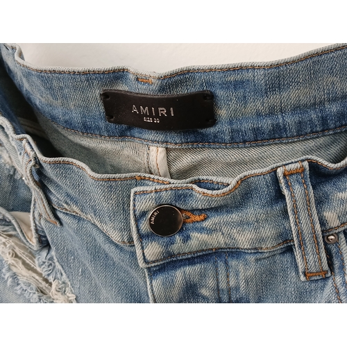 959 - A pair of Amiri light wash distressed skinny jeans featuring heavy ripped details throughout the leg... 