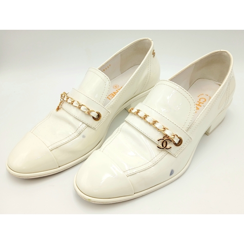 594 - A pair of Chanel White Patent Leather Chain Loafers. Gold-tone CC charm and chain detail across the ... 