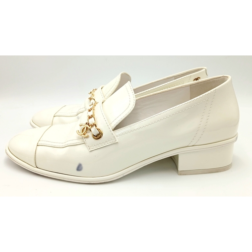 594 - A pair of Chanel White Patent Leather Chain Loafers. Gold-tone CC charm and chain detail across the ... 