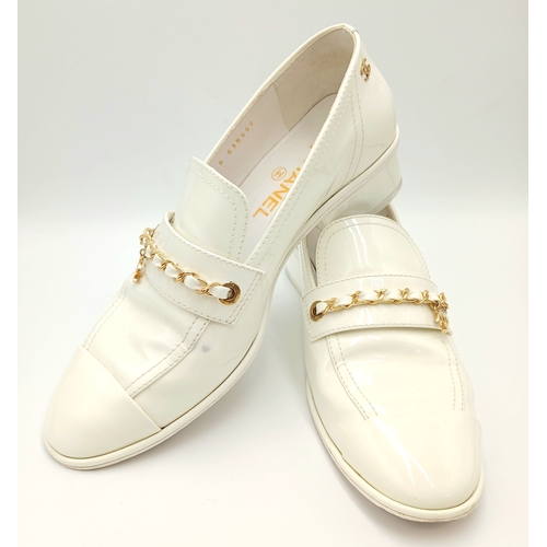594 - A pair of Chanel White Patent Leather Chain Loafers. Gold-tone CC charm and chain detail across the ... 