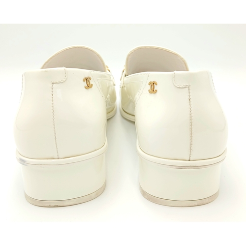 594 - A pair of Chanel White Patent Leather Chain Loafers. Gold-tone CC charm and chain detail across the ... 
