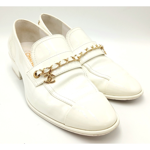 594 - A pair of Chanel White Patent Leather Chain Loafers. Gold-tone CC charm and chain detail across the ... 