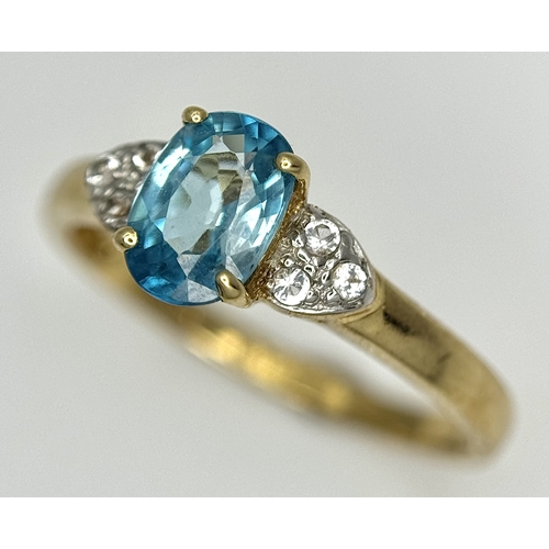 643 - A 9K Yellow Gold Blue Zircon and White Topaz Ring. 0.957ct Cambodian oval cut centre stone with 0.06... 
