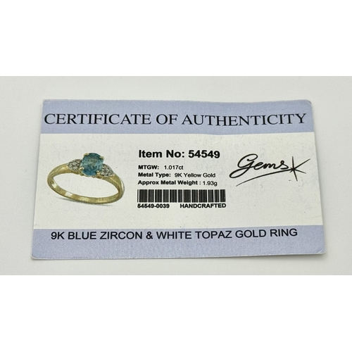 643 - A 9K Yellow Gold Blue Zircon and White Topaz Ring. 0.957ct Cambodian oval cut centre stone with 0.06... 