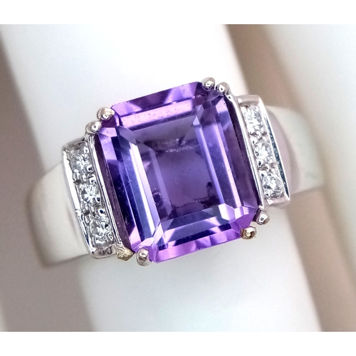 615 - An 18K White Gold (tested) Amethyst and Diamond Ring. A 2.5ct step cut amethyst with a three round b... 