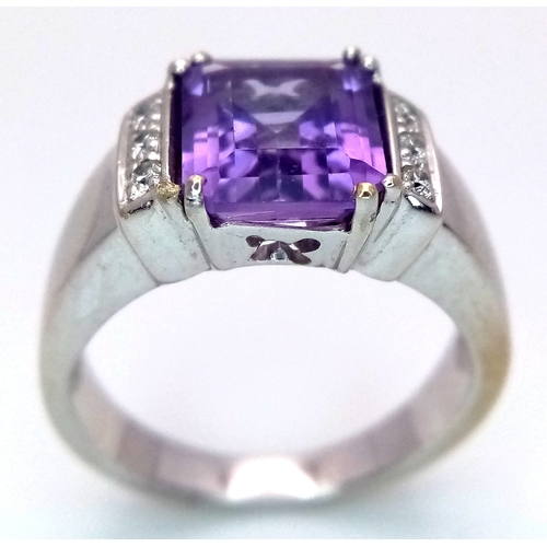 615 - An 18K White Gold (tested) Amethyst and Diamond Ring. A 2.5ct step cut amethyst with a three round b... 