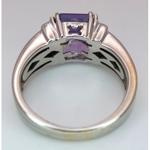615 - An 18K White Gold (tested) Amethyst and Diamond Ring. A 2.5ct step cut amethyst with a three round b... 