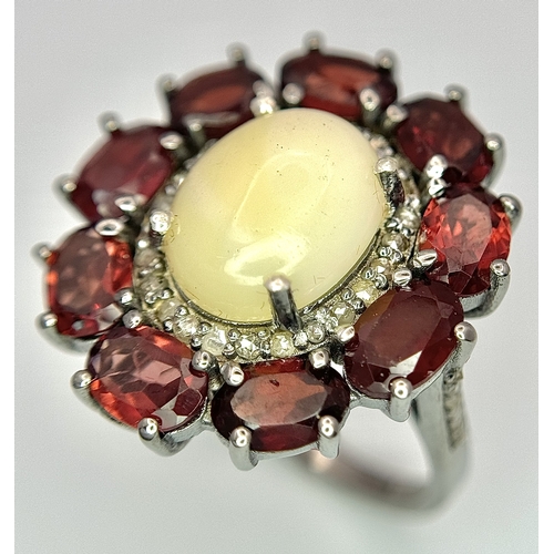 831 - An Opal, Garnet and Diamond Ring. Central 2ct opal cabochon with garnet and diamond surround. Set in... 
